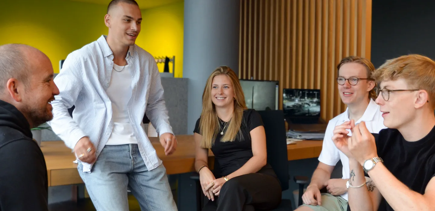 Five young people in a modern office, three men and two women, talking and smiling.