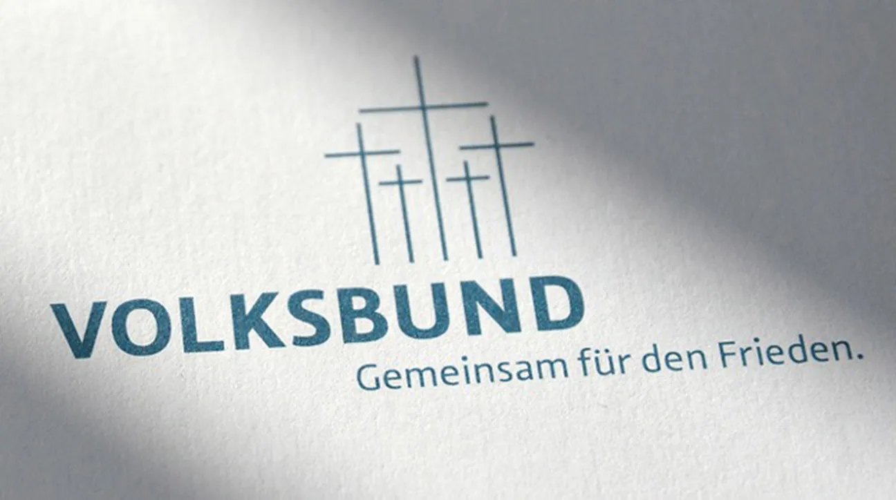 Logo des Volksbund Deutsche Kriegsgräberfürsorge e.V. mit drei Kreuzen und dem Slogan "Gemeinsam für den Frieden." auf weißem Papier.