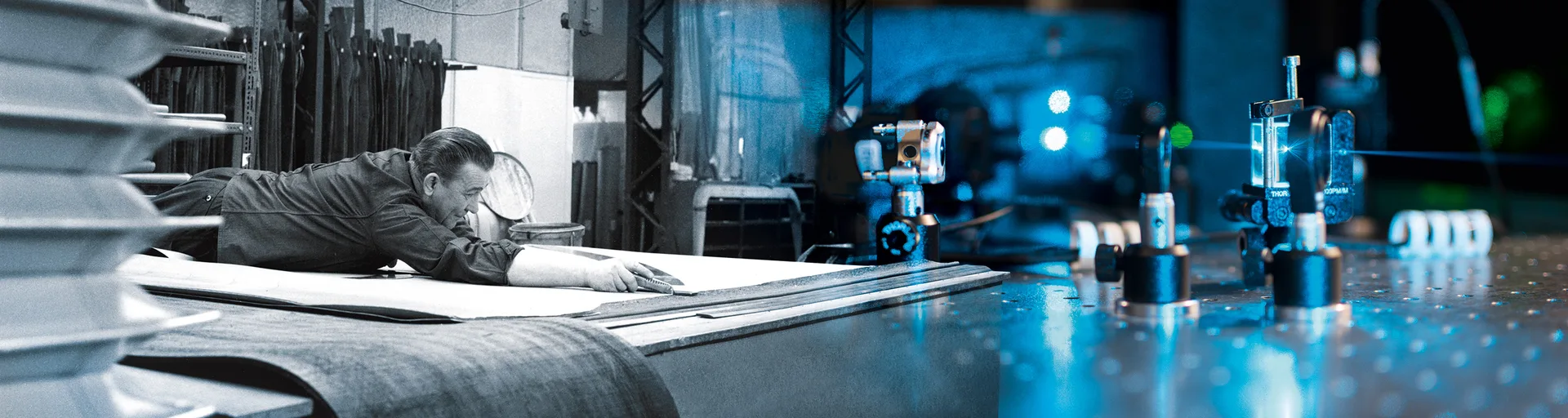 Ein Mann arbeitet an einem großen Stoffstück, während im Hintergrund eine Laseranlage mit blauem Lichtstrahl zu sehen ist.